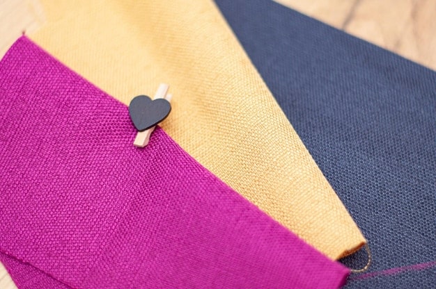 A close-up shot of various blazer fabrics, textures, and colors arranged on a flat surface. Examples include tweed, linen, cotton, and velvet, showcasing the wide range of options available for different seasons and styles.