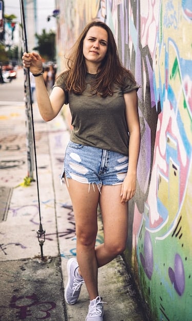 A woman wearing a casual outfit consisting of a graphic tee, distressed denim shorts, and ankle boots, brought together by a brightly colored (e.g., red or yellow) blazer. The blazer adds a pop of color and elevates the edginess of the shorts.
