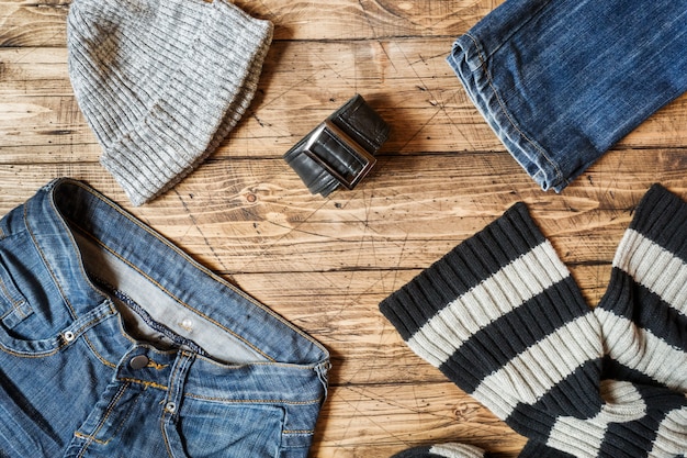 A well-organized closet with various casual clothing items: jeans, t-shirts, sweaters, sneakers, and a denim jacket. The clothes are neatly arranged by color and type, creating a visually appealing and accessible wardrobe.