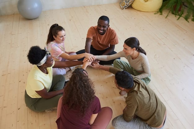 A diverse group of people sitting in a circle, holding hands, and smiling genuinely at each other. The setting is a bright, airy room with plants in the background, suggesting a support group meeting.