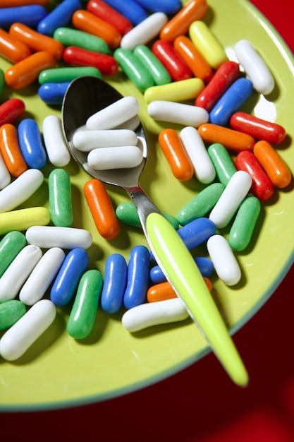 A close-up shot of various multivitamin pills scattered on a table, with a focus on the labels and ingredient lists. The composition emphasizes the complex formulations and marketing claims of these supplements.