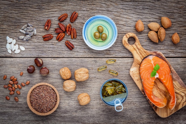 A close-up shot of various foods rich in omega-3 fatty acids, such as salmon, flaxseeds, walnuts, and chia seeds, arranged on a wooden cutting board in a well-lit kitchen setting.