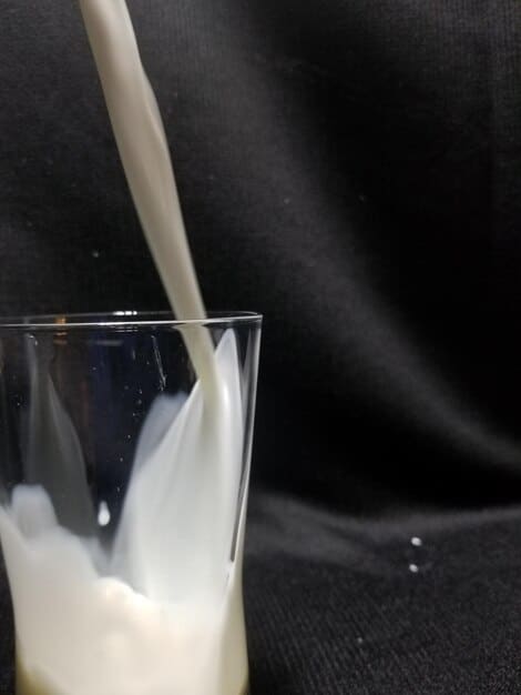 A close-up of a post-workout protein shake being poured into a glass, highlighting the creamy texture and the condensation on the glass, suggesting refreshment and recovery.