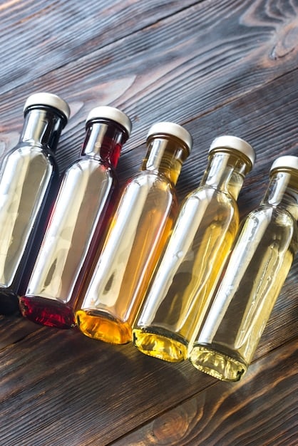 A close-up shot of various small glass bottles filled with different natural fragrance oils like lavender, sandalwood, and citrus. The bottles are neatly arranged on a wooden table, with droppers ready for blending.
