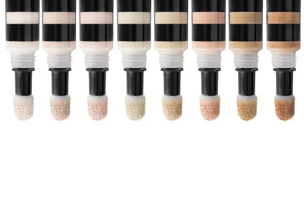 A detailed flat lay of various color correcting sticks and liquid concealers arranged by color on a light background. There are brushes and beauty sponges nearby. The lighting is soft and even, highlighting the different textures and shades.