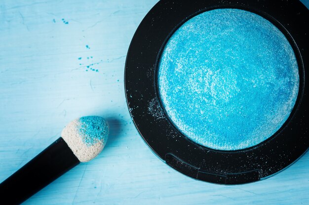 A close-up shot of a beauty blender pressing a generous amount of translucent setting powder onto the under-eye area of a model's face, highlighting the matte, white layer of powder.
