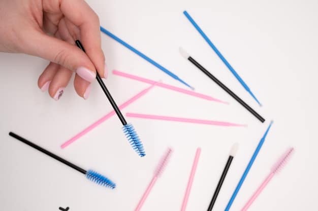 Detailed close-up of a hand applying a thin line of adhesive to the band of a false eyelash strip using a small brush.