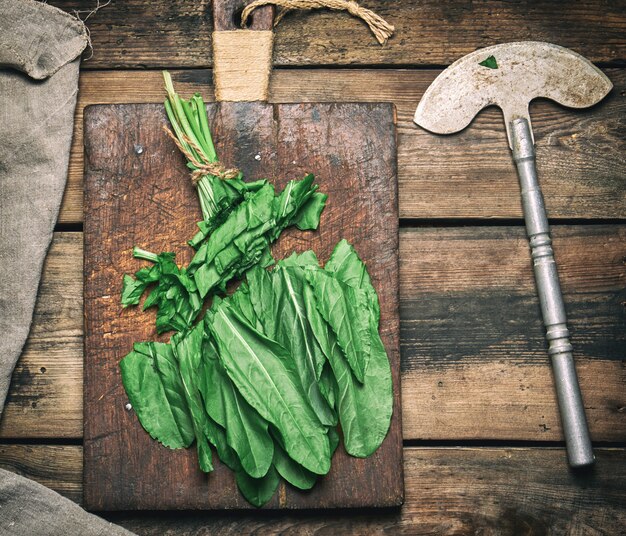 A close-up shot of fresh collard greens, clearly showing their broad, sturdy leaves and deep green color, perhaps on a rustic wooden cutting board, implying cooking preparation.