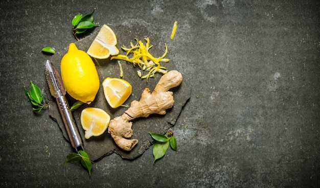 Fresh ginger root and multiple slices of ginger elegantly arranged on a dark, textured surface, with small green leaves adding a touch of freshness, suggesting natural healing.