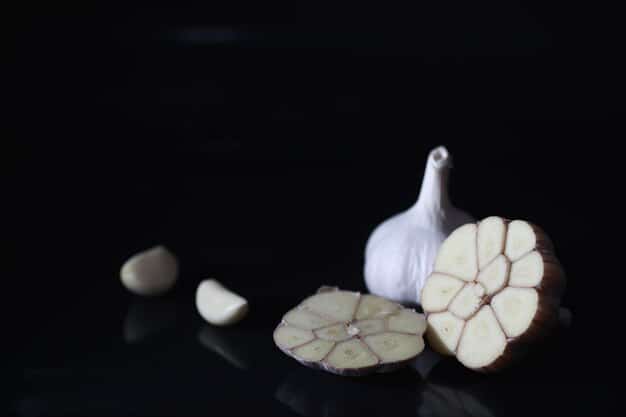 A close-up shot of a single garlic bulb with several individual cloves artfully arranged around it on a textured, dark background, highlighting its natural segments and rustic appeal.