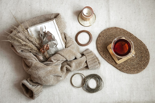 A flat lay of stylish Fall 2025 accessories on a wooden surface, including a structured leather handbag in a deep red tone, a pair of elegant long leather gloves, a patterned silk scarf loosely draped, a sophisticated fedora hat, and a collection of gold rings and a statement watch. The arrangement conveys a sense of curated luxury and autumnal warmth.