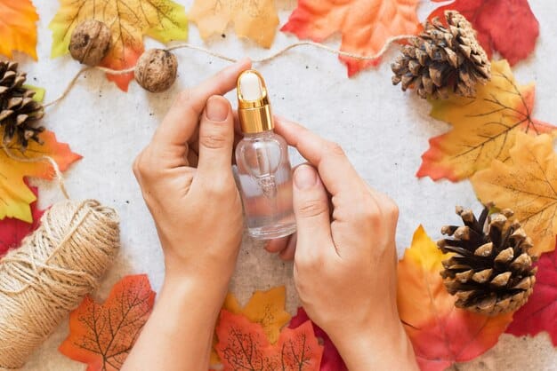 A close-up of a person's wrist with a dab of perfume, surrounded by small glass vials of essential oils and autumn leaves, suggesting the process of fragrance blending.