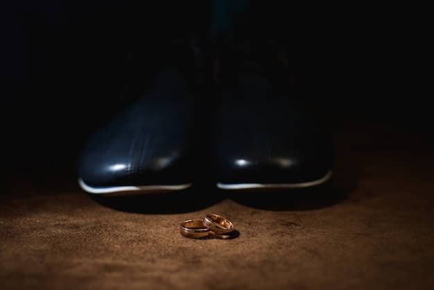 A close-up shot of a pair of polished, dark brown leather loafers with a subtle gold chain detail on the vamp, resting on a rustic wooden floor with a hint of autumn leaves in the background.