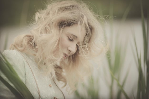 A woman with lustrous, sandy blonde hair styled in soft waves, with light catching the subtle warm undertones, against a minimalist winter backdrop.