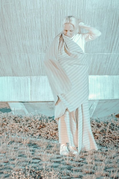 A striking, conceptual gown by Kai Chen made from geometric panels of iridescent fabric, reflecting light dramatically. The model is standing in an abstract, dark gallery space, highlighting the garment as a piece of art.