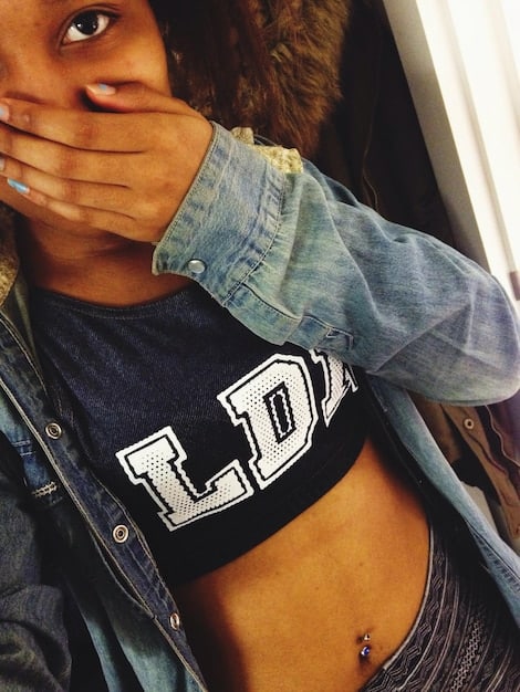 A close-up shot of a model's layered outfit, featuring a vintage graphic band t-shirt peeking from under an open plaid flannel shirt, with a detailed view of ripped knee denim jeans and a studded leather belt, conveying authenticity and texture, in an urban setting.