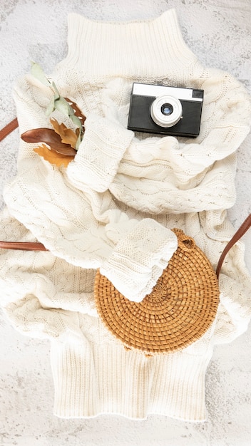 A flat lay photograph showcasing a carefully curated modern grunge outfit, including a neutral-toned plaid flannel, a soft black beanie, a pair of slightly oversized distressed jeans, a vintage Nirvana t-shirt, and shiny black combat boots, all arranged aesthetically on a rough wooden surface.