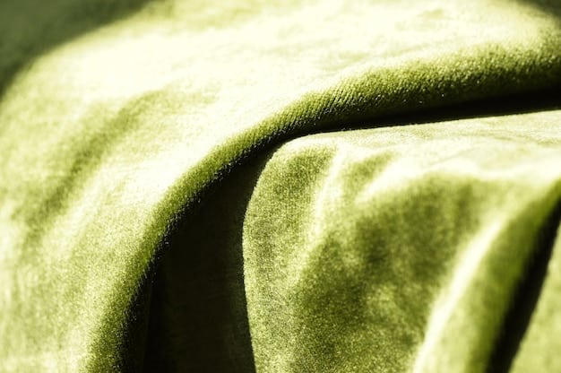 A close-up of a designer fabric swatch in a sophisticated moss green, with subtle textures and a soft drape, representative of organic material.