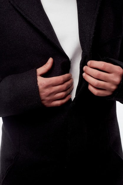 A close-up shot of a meticulously tailored wool blazer with a cinched waist via a broad fabric belt, highlighting the attention to detail in defining the silhouette for a Fall/Winter 2025 collection.