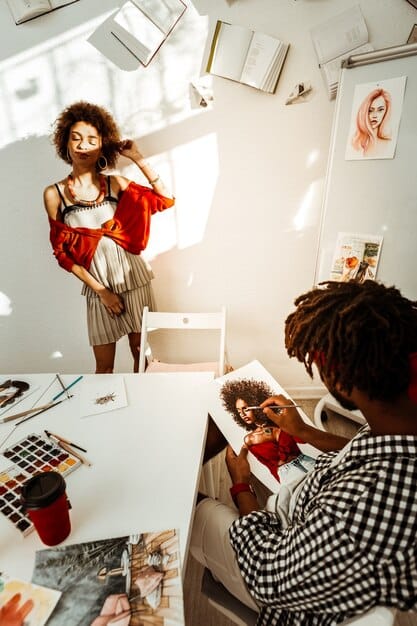 A diverse group of young fashion designers collaborating on a digital mood board displayed on a large screen, incorporating elements from various social media feeds.