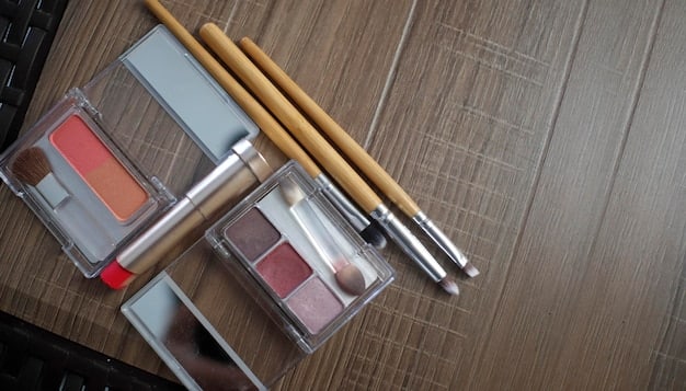 A neatly arranged makeup station featuring essential items for a cut crease look: a variety of eyeshadow palettes in neutral and bold colors, a set of makeup brushes including blending and precision brushes, a concealer palette, and a tube of eyeshadow primer.