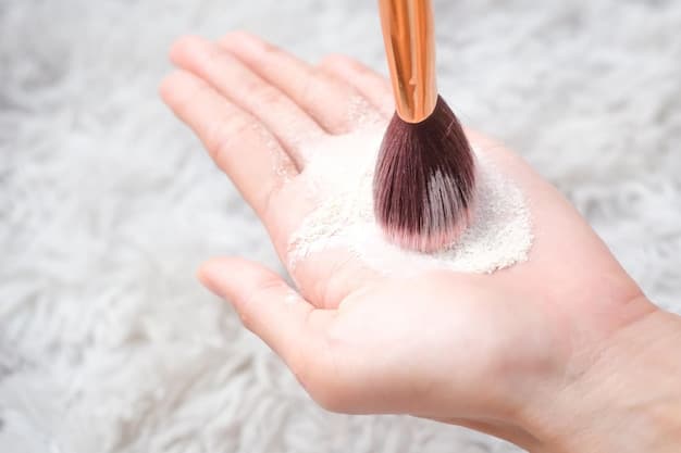 A hand applying a generous layer of translucent powder under the eye with a makeup sponge for baking. The skin is fair and the powder is light.