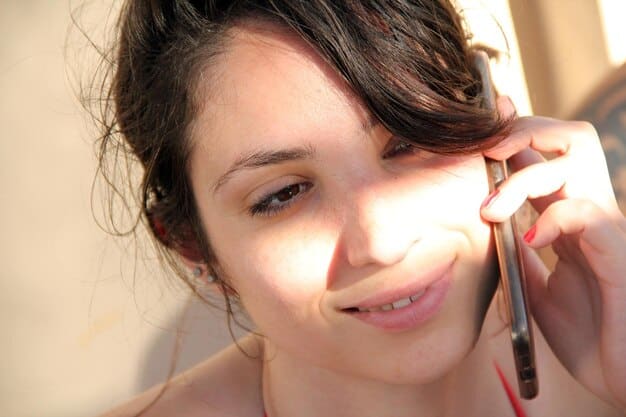 A woman applying highlighter to her cheekbone. The photo showcases the shimmer and glow that the highlighter adds to the skin, enhancing her features for a night-out makeup look. Light is reflecting off the highlighter.