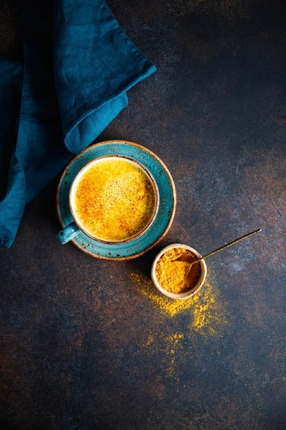 An overhead shot of a steaming mug filled with golden-colored turmeric latte. The mug is placed on a rustic wooden table, surrounded by cinnamon sticks, star anise, and a small bowl of ground turmeric. The warm lighting and aromatic spices create a cozy and inviting atmosphere, highlighting the potential comfort and cognitive benefits of incorporating turmeric into a diet to Boost Your Brainpower: 5 Foods Proven to Sharpen Focus in 30 Days.