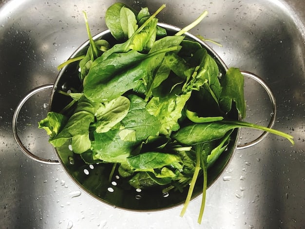 A close-up shot of vibrant green spinach leaves being washed in a stainless steel colander. Water droplets cling to the leaves, conveying freshness and cleanliness. The focus is on the texture and vivid color of the spinach, emphasizing its natural appeal within the context of Beyond Kale: 5 Underrated Greens Packed with Nutrients You Need Now.