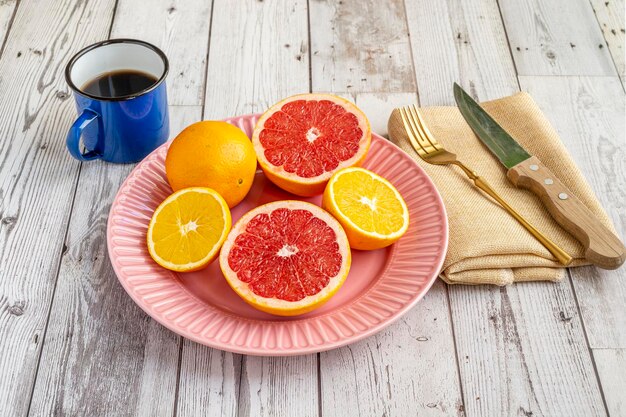 Close-up shot of halved oranges, lemons, and grapefruits arranged artfully on a white plate. The emphasis is on the vibrant colors and textures of the citrus fruits, highlighting their freshness and appeal. The background is a soft, blurred kitchen setting.