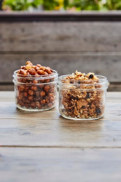 A close shot featuring a small, clear container filled with pre-portioned snacks, including mixed nuts, dried fruit, and a few dark chocolate squares. The container is set on a wooden desk near a laptop and notepad, suggesting a planned, healthy snacking routine. This scene illustrates the convenience and intentionality of preparing healthy snacks, aligning with The Ultimate Guide to Healthy Snacking: 10 Options Under 200 Calories.