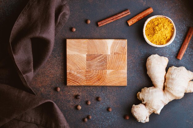 A rustic wooden cutting board showcasing freshly peeled and sliced ginger root alongside whole turmeric roots and a sprinkle of ground black pepper, emphasizing preparation of natural remedies.
