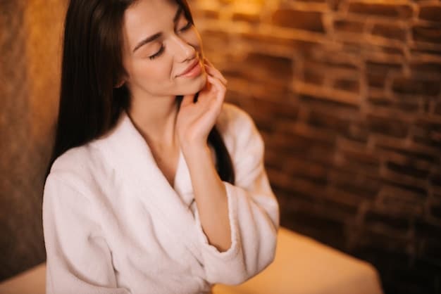 A woman gently massaging facial oil onto her cheeks in a cozy, dimly lit room, emphasizing the relaxing and nourishing aspect of a winter skincare ritual. Soft focus on the oil bottle and her hands. The oil provides key benefits to the Winter Skincare Routine: Combat Dryness and Achieve Glowing Skin with These 6 Hydrating Products in 2025.