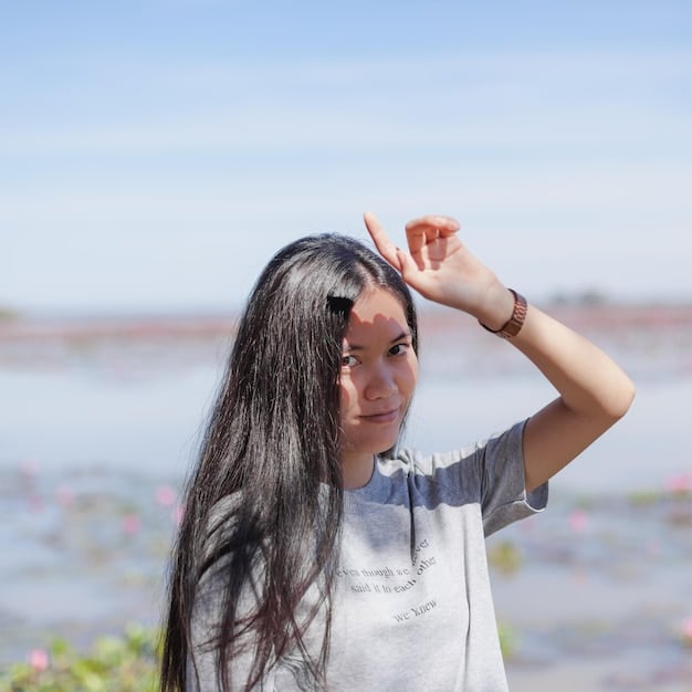 A person applying sunscreen to their scalp along the hairline. The image shows the ease of use of spray sunscreen and emphasizes the importance of protecting the scalp from sun damage. The image complements the discussion of Summer Haircare: Protect Your Locks from Sun Damage with These 5 Essential Products in 2025.