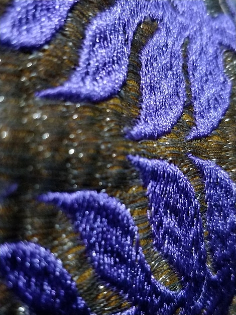 A detailed close-up of intricate embroidery on a flowing garment, possibly from an emerging designer's collection, highlighting textile innovation and craftsmanship, with a soft, natural light illuminating the textures.